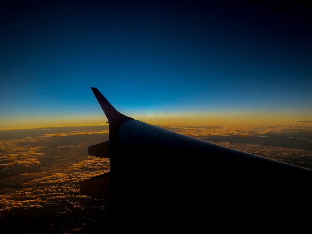 Airplane wing over mountains at sunset